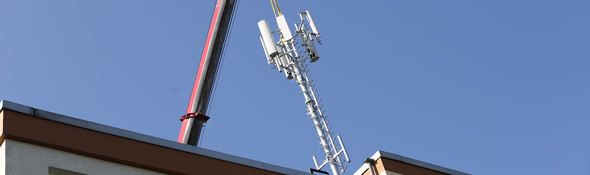 Techniker bauen Mobilfunkantennen auf einem Hausdach auf